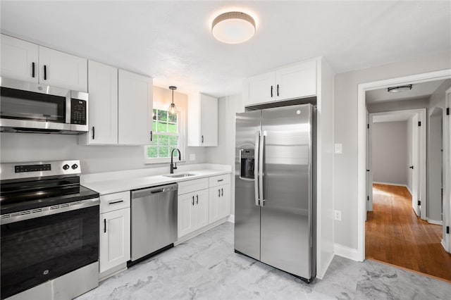 kitchen with white cabinets, light hardwood / wood-style flooring, stainless steel appliances, sink, and decorative light fixtures