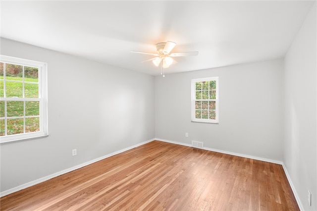 unfurnished room with ceiling fan, wood-type flooring, and a wealth of natural light