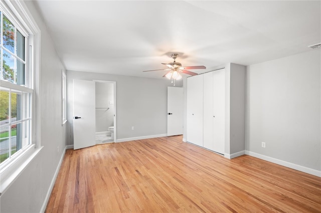 empty room featuring ceiling fan, a wealth of natural light, and light wood-type flooring