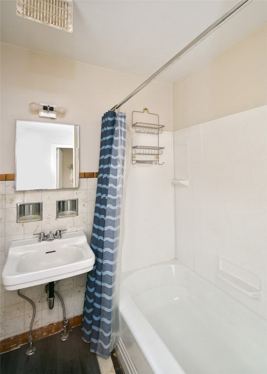 bathroom with sink, shower / bath combination with curtain, wood-type flooring, and tile walls