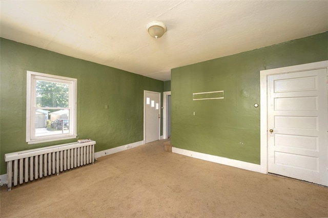 carpeted empty room featuring radiator heating unit