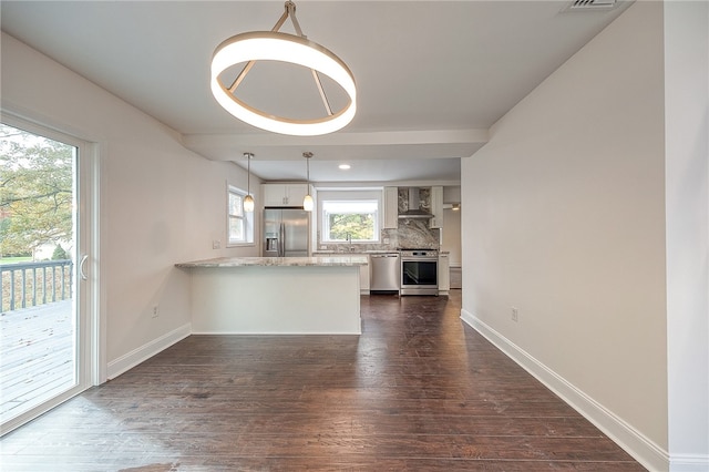 kitchen with wall chimney range hood, kitchen peninsula, stainless steel appliances, and a healthy amount of sunlight