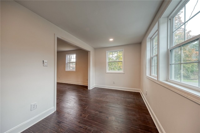 unfurnished room featuring plenty of natural light and dark hardwood / wood-style flooring