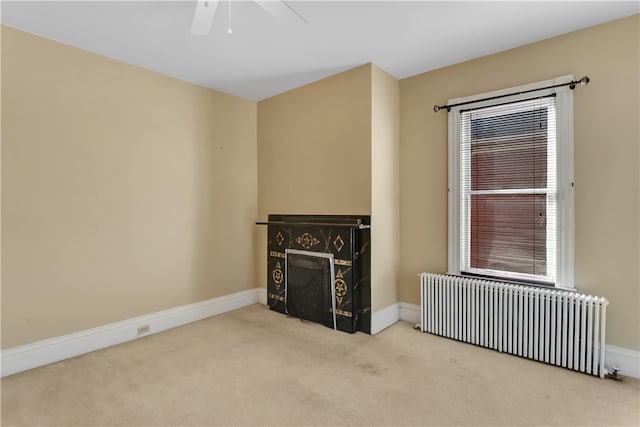 unfurnished living room featuring ceiling fan, light colored carpet, and radiator