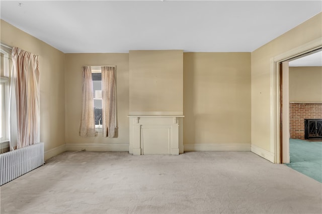 unfurnished room featuring radiator, a fireplace, and light colored carpet