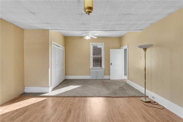 spare room featuring radiator heating unit, hardwood / wood-style flooring, and ceiling fan