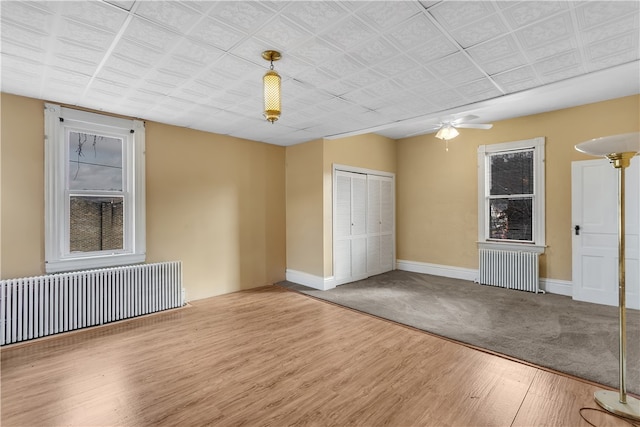 spare room featuring hardwood / wood-style floors, radiator heating unit, and ceiling fan