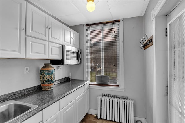 kitchen with plenty of natural light, white cabinetry, and radiator