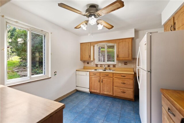 kitchen featuring white appliances, a wealth of natural light, and sink