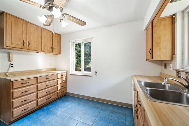 kitchen with dark tile patterned floors, sink, and ceiling fan