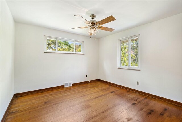 unfurnished room featuring a wealth of natural light, wood-type flooring, and ceiling fan