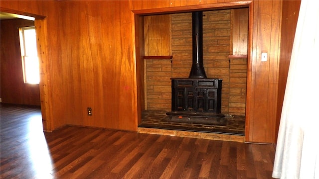 unfurnished living room featuring a wood stove, wood walls, and dark hardwood / wood-style flooring