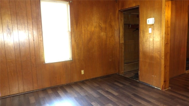 unfurnished room featuring dark hardwood / wood-style flooring and wooden walls