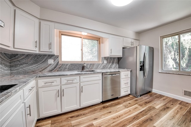 kitchen featuring light wood-type flooring, white cabinetry, stainless steel appliances, and a healthy amount of sunlight