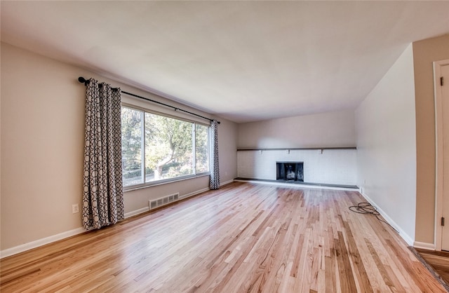 unfurnished living room featuring a fireplace and light hardwood / wood-style floors