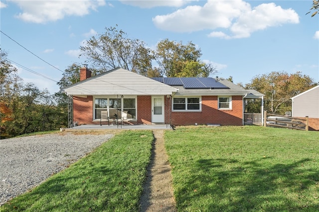 view of front of property featuring a patio area, a front yard, and solar panels