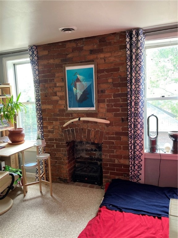 carpeted bedroom featuring multiple windows and a brick fireplace