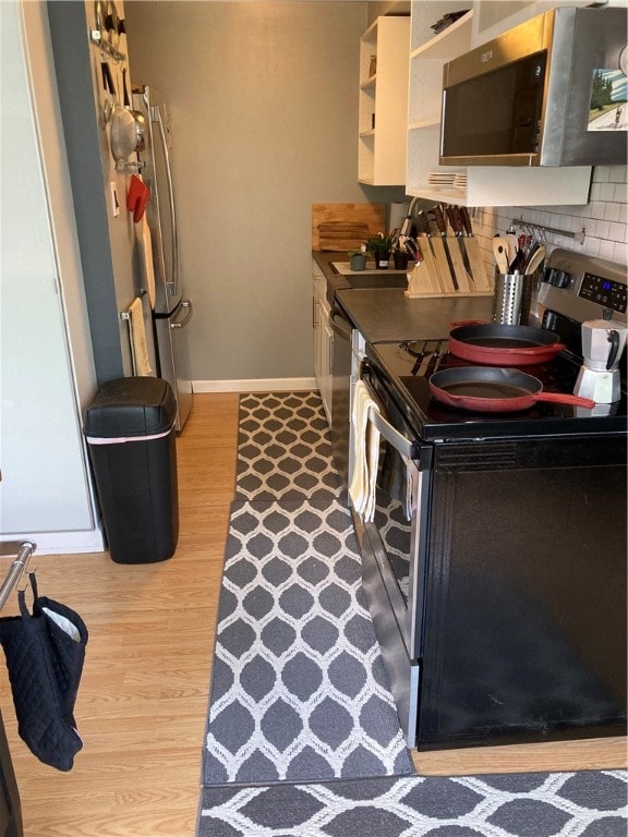 kitchen with decorative backsplash, appliances with stainless steel finishes, and light wood-type flooring