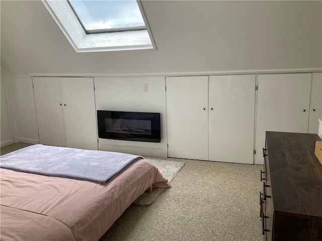 bedroom featuring a closet, carpet flooring, and vaulted ceiling with skylight