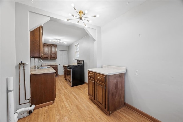 kitchen featuring gas stove, dark brown cabinets, sink, light hardwood / wood-style floors, and lofted ceiling