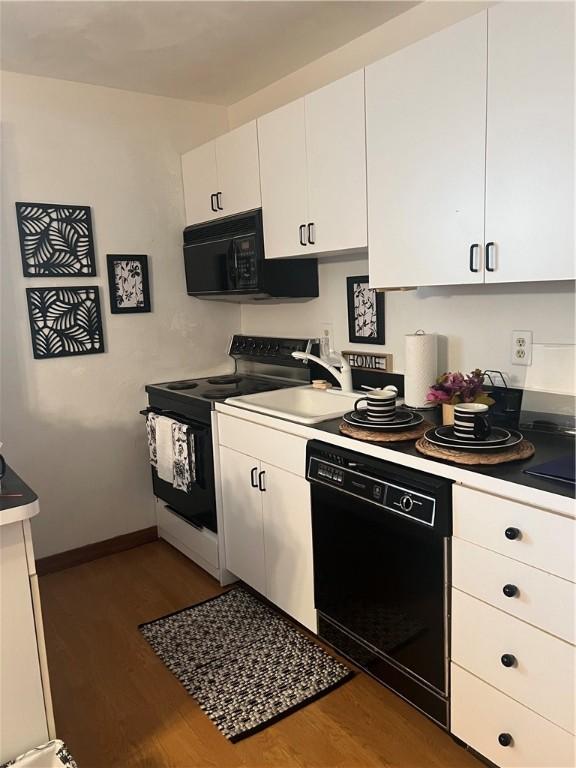 kitchen with black appliances, white cabinetry, and dark wood-type flooring