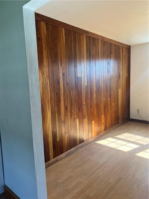 empty room featuring light hardwood / wood-style flooring and wooden walls