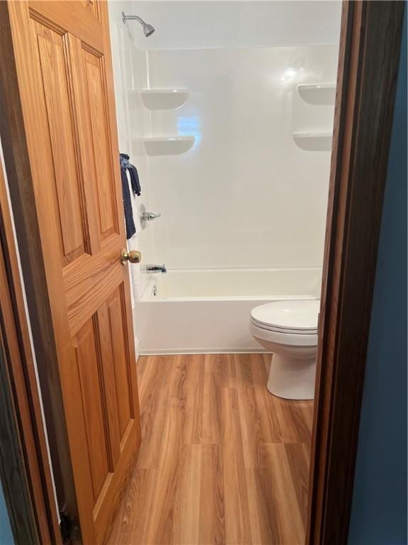 bathroom with wood-type flooring, shower / bathtub combination, and toilet