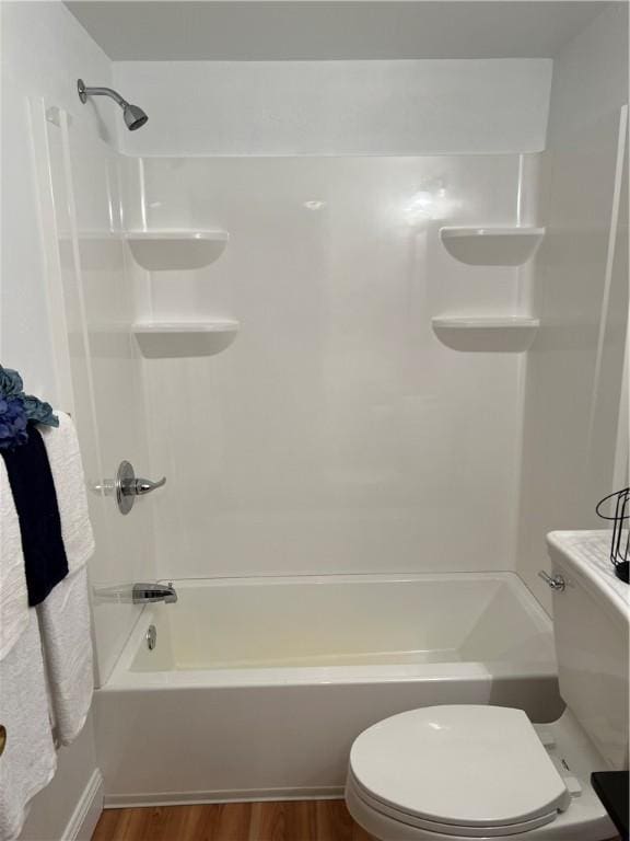 bathroom with wood-type flooring,  shower combination, and toilet