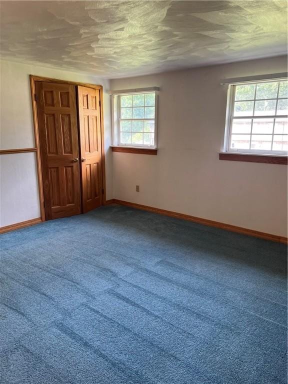 unfurnished bedroom featuring carpet flooring, a textured ceiling, and multiple windows