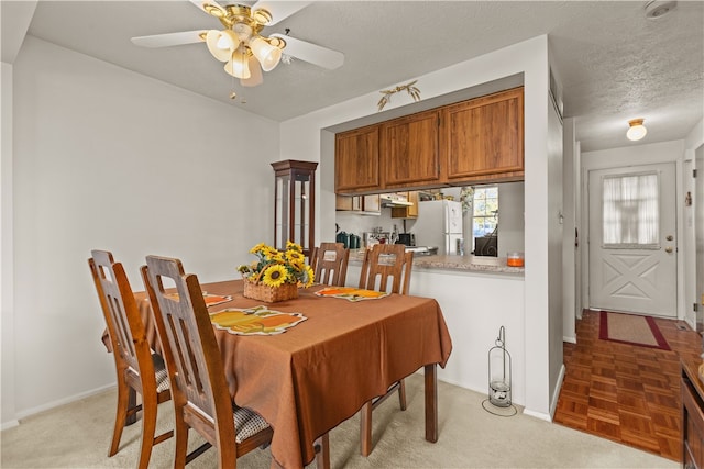 dining area with light carpet, a textured ceiling, and ceiling fan