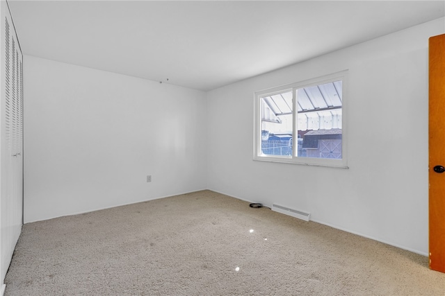 carpeted empty room featuring baseboard heating