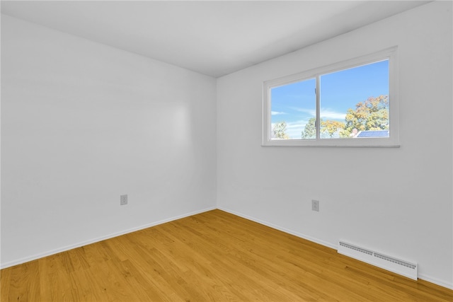 unfurnished room with a baseboard radiator and wood-type flooring