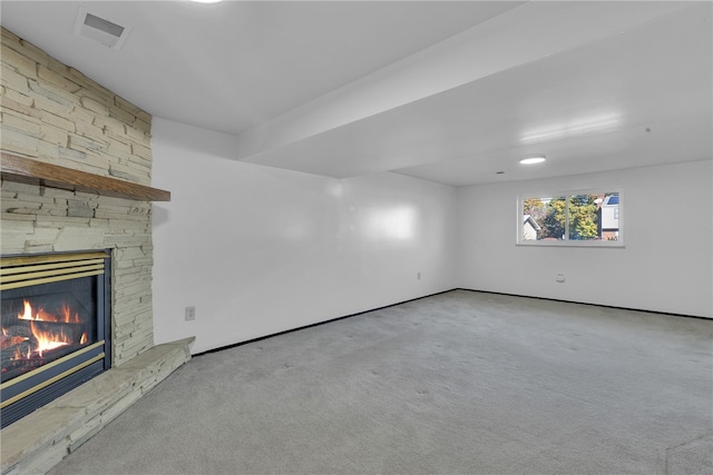 unfurnished living room featuring a stone fireplace and light colored carpet