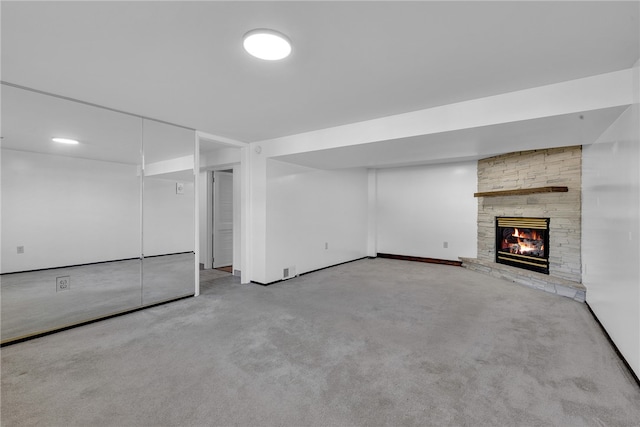 basement with light carpet and a stone fireplace