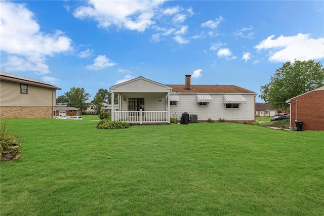 rear view of house with central AC and a lawn