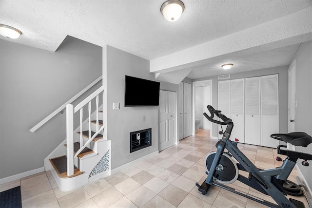 workout room with a textured ceiling and light tile patterned floors