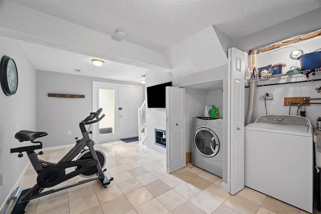 laundry room with a textured ceiling, light tile patterned floors, and washing machine and clothes dryer