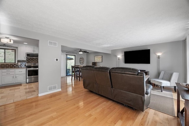 living room featuring a wealth of natural light, light hardwood / wood-style floors, and ceiling fan