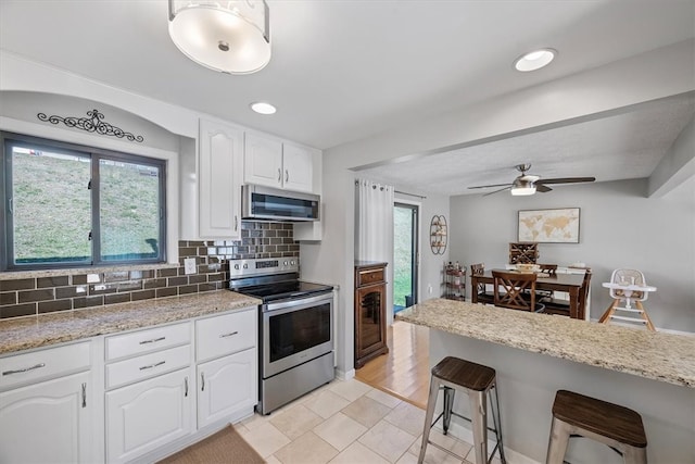 kitchen with white cabinetry, tasteful backsplash, stainless steel appliances, and a kitchen bar