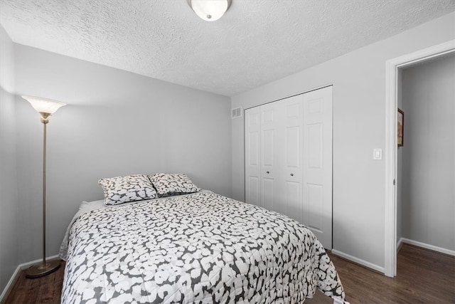 bedroom with dark wood-type flooring, a textured ceiling, and a closet