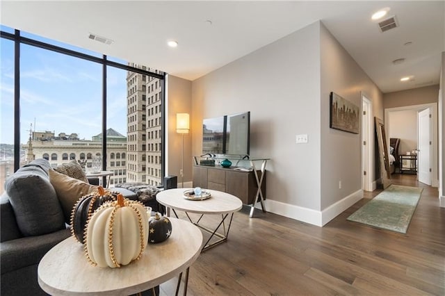 living room with dark hardwood / wood-style flooring and a wall of windows