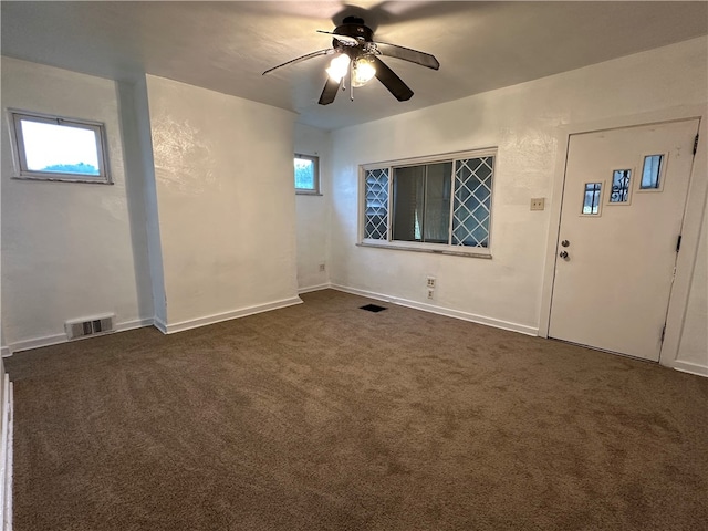 foyer entrance with ceiling fan and dark colored carpet