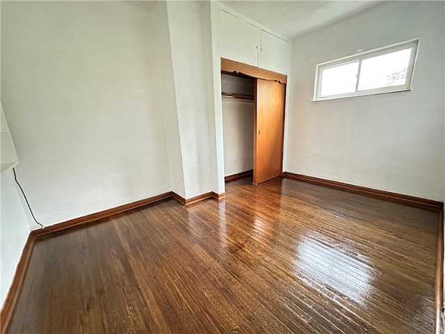 unfurnished bedroom featuring a closet and dark hardwood / wood-style flooring