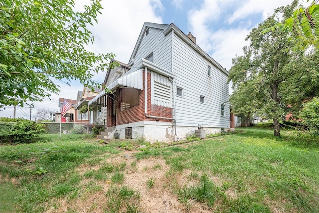 view of side of property with a lawn and central AC unit