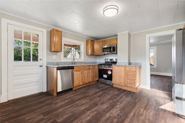 kitchen with sink, crown molding, dark hardwood / wood-style floors, light stone countertops, and stainless steel appliances