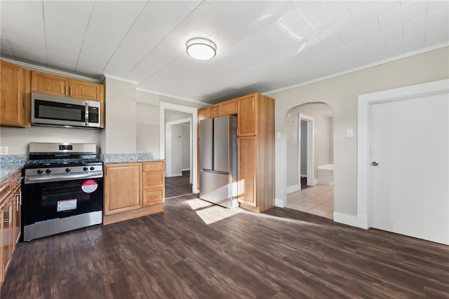 kitchen with stone counters, appliances with stainless steel finishes, dark hardwood / wood-style floors, and ornamental molding