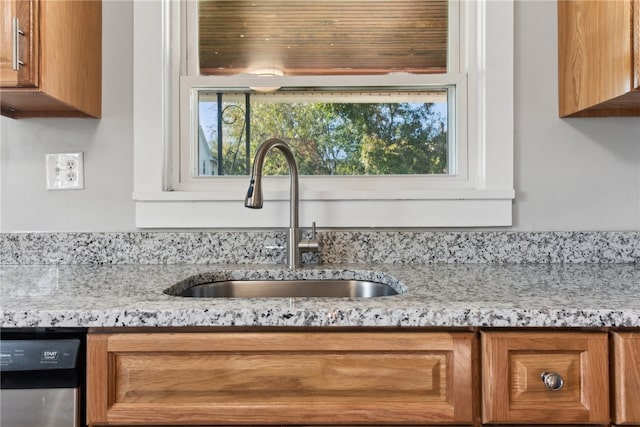 room details featuring light stone countertops, stainless steel dishwasher, and sink