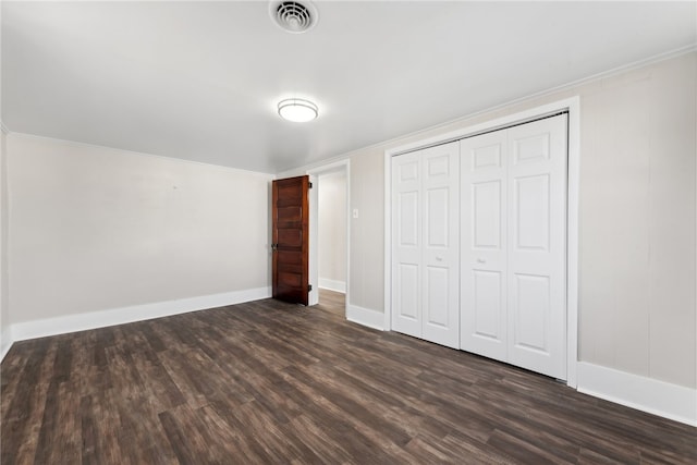 unfurnished bedroom featuring a closet, dark hardwood / wood-style floors, and ornamental molding