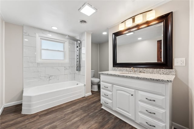 full bathroom with vanity, wood-type flooring, tiled shower / bath combo, and toilet