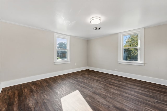 spare room with dark hardwood / wood-style flooring, ornamental molding, and a wealth of natural light